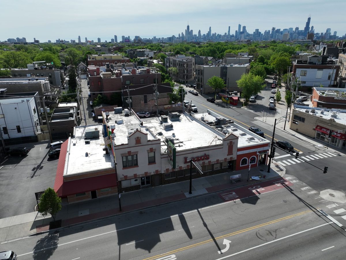 Aerial view of a Chicago commercial corner building with rooftop units and the skyline behind